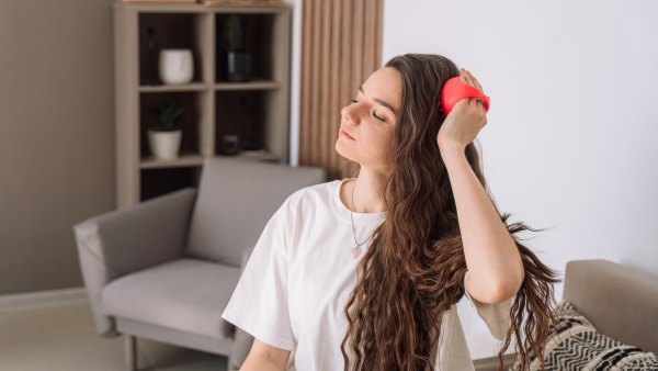 Lady takes care of scalp by doing massage with scalp massager.