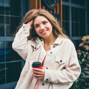 Blonde girl student girl smiles and walks around the city and stands on the background of a cafe, restaurant. Portrait of a girl in the city
