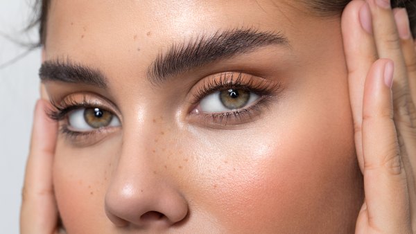 Closeup studio shot of a beautiful woman with freckles skin posing against a grey background