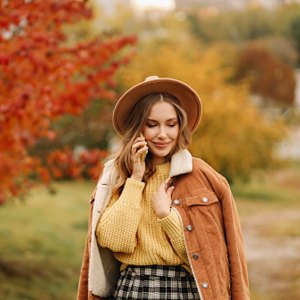 woman wearing jacket, sweater, skirt and hat in autumn setting