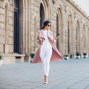 woman walking on street wearing pink blazer and white pants