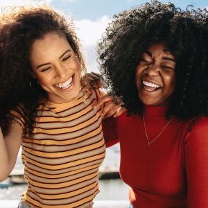 Cheerful young women enjoying a day out on the beach. Female friends having fun on the sea shore.