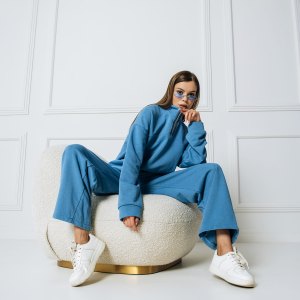Fashion model woman sitting in a chair posing in a new collection of sportswear.