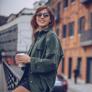 woman sitting on a railing drinking coffee