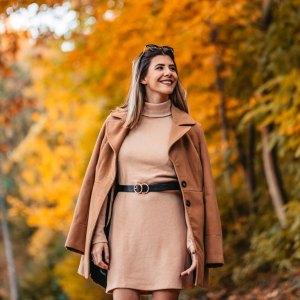 a woman walking through a park in the fall