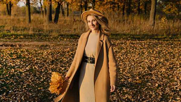 woman wearing beige coat, dress and hat in the fall