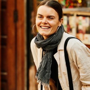 Wide shot of solo female traveler laughing while taking photographs in the medina of Marrakech during vacation in Morocco
