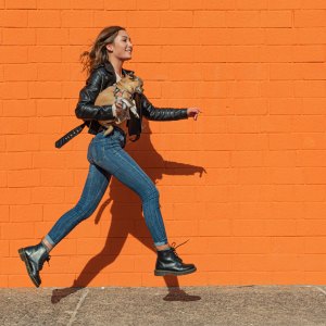 woman wearing leather jacket skipping on a street