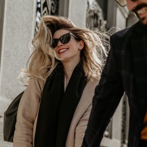 woman in sunglasses walking down a street with a man