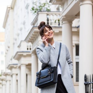 Elegant beautiful woman talking on phone in front of city houses