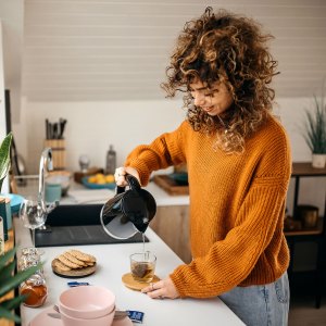 Cropped shot of an attractive young woman making herself some tea in her small kitchen at home