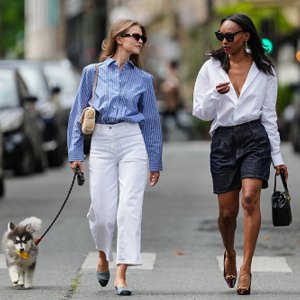 two women walking dog in city