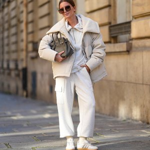 woman wearing beige coat, sweatpants, sneakers and a purse