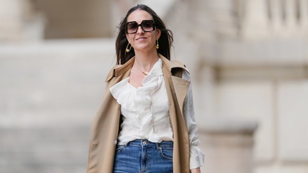 woman wearing white fall top, beige vest and blue jeans