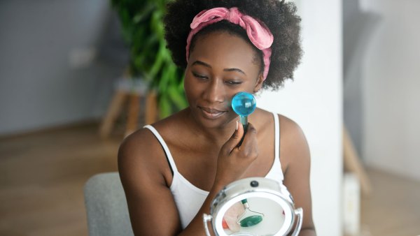 Young beautiful woman enjoying a facial massage with ice globes at home.