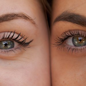 Close up view of two women with her faces next to each other while looking at the camera.