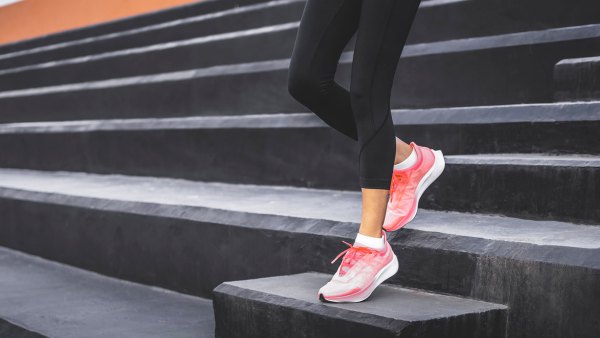 Stairs climbing running woman doing run down steps on staircase. Female runner athlete going down stairs in urban city doing cardio sport workout run outside during summer. Activewear leggings and shoes.