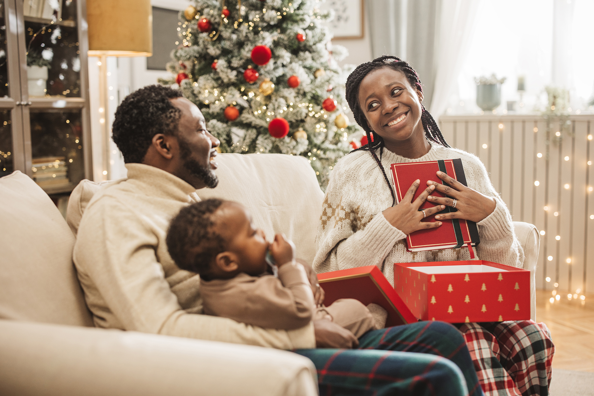 Young family unwrapping gifts on Christmas morning. Mother is getting cookbook.