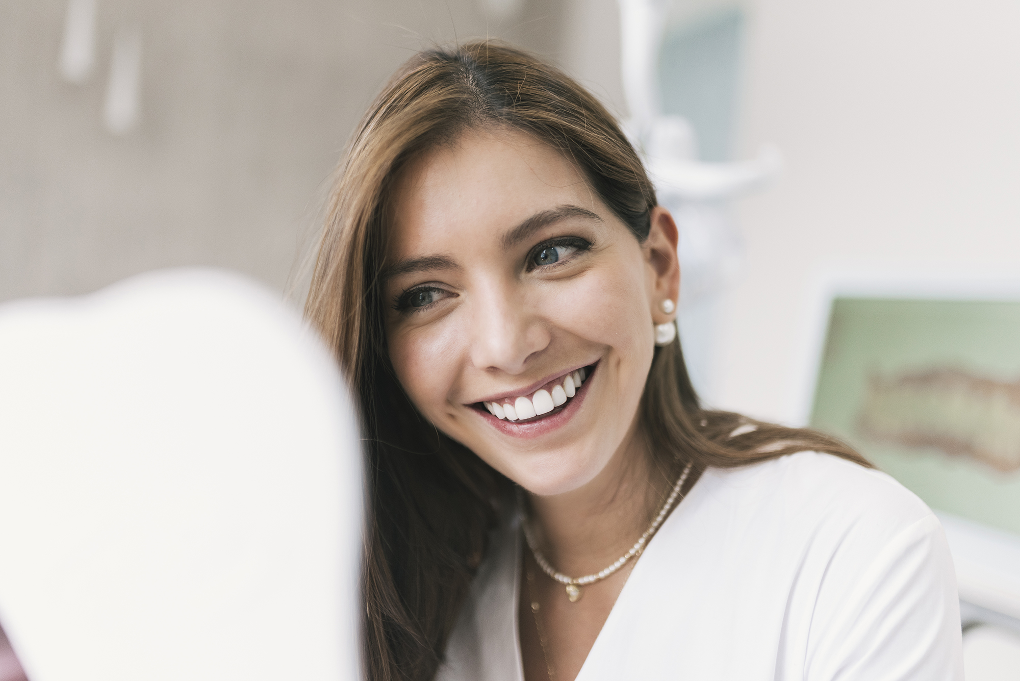 Happy woman looking at mirror at dentist's clinic