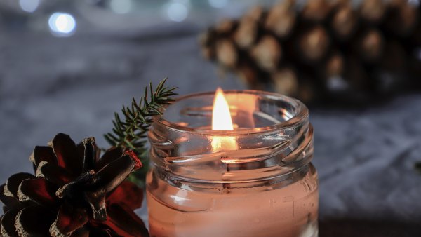 Lit,scented, mason jar candle with pine cones and bokeh/Christmas decoration