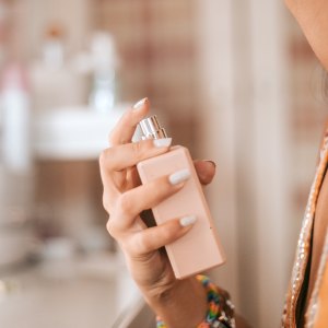 closeup woman spraying perfume on wrist