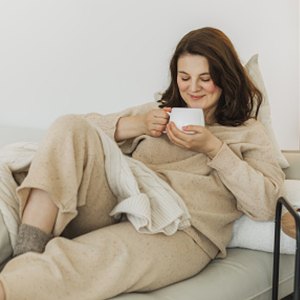 woman wearing beige loungewear set sipping a cup of tea