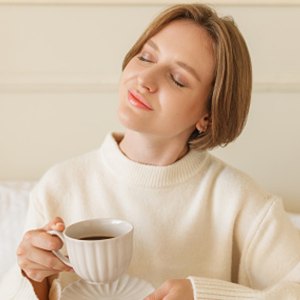 woman wearing loungewear in bed drinking coffee