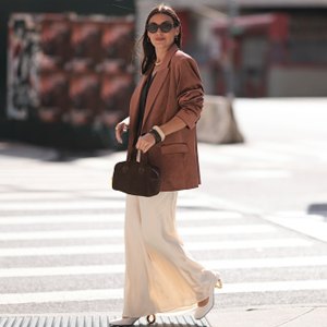 woman wearing brown blazer, white skirt and brown bag walking on street