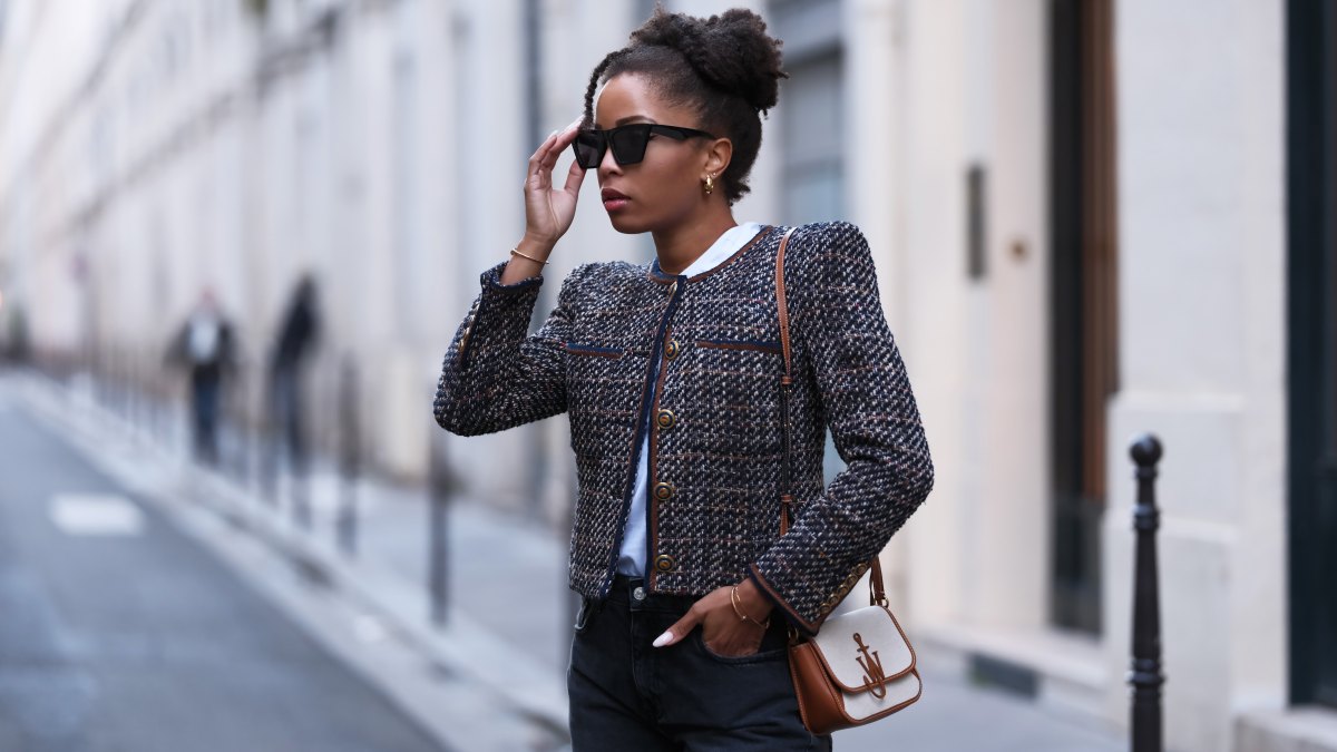 PARIS, FRANCE - NOVEMBER 06: Ellie Delphine wears sunglasses, a white t-shirt, a tweed jacket with bronze buttons from Veronica Beard, flared denim / jeans pants from Zara, a brown and white JW Anderson bag, during a street style fashion photo session, on November 06, 2023 in Paris, France. (Photo by Edward Berthelot/Getty Images)