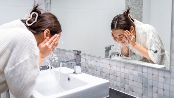 Woman washing her face with facial foam and water