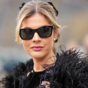 PARIS, FRANCE - MARCH 07: Lala Rudge wears black sunglasses, diamonds earrings, a black velvet with lace print pattern halter-neck long dress, a black feathers cloak, outside Chanel, during Paris Fashion Week - Womenswear Fall Winter 2023 2024, on March 07, 2023 in Paris, France. (Photo by Edward Berthelot/Getty Images)