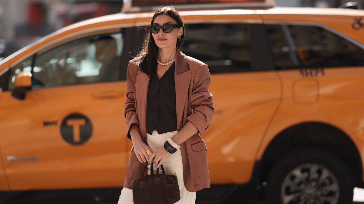 Yana Echko seen wearing YSL brown sunglasses, Bottega Veneta brown leather earrings, white pearl necklace, The Frankie Shop brown pinstripe vest, Express light brown corduroy blazer jacket, Reformation cream white maxi silk long skirt, MARGE SHERWOOD brown suede leather small bag, Kenneth Jay Lane gold ring, cream white / brown bangle, outside the Bach Mai show, during the New York Fashion Week, on September 08, 2024 in New York City.