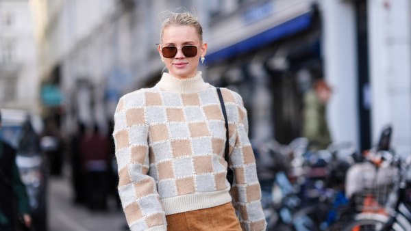 A guest wears sunglasses, a white and beige checkered / checked pattern printed turtleneck ribbed wool pullover with shoulder pads, a beige / brown suede mini skirt , outside Mark Kenly Domino Tan, during the Copenhagen Fashion Week AW24 on February 01, 2024 in Copenhagen, Denmark.