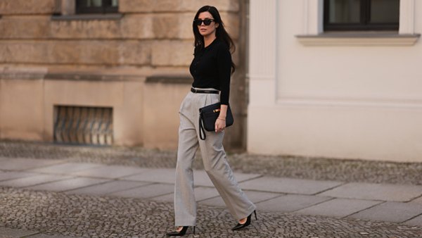 Leo Eberlin seen wearing Bottega Veneta black sunglasses, Leo Mathild jewelry / diamond bracelet and rings, Allude x Leo Mathild cashmere wool knit buttoned body, Toteme black leather belt, Velaa light grey elegant suit pants, Hermès black leather clutch bag and Saint Laurent black varnished leather heels / pumps, on February 25, 2024 in Berlin, Germany.