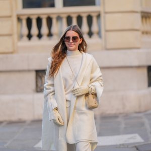 Diane Batoukina wears brown Dior sunglasses, a white cashmere Zara turtleneck pullover, matching coat and pants, a light brown fluffy faux fur Prada bag, white leather gloves, during a street style fashion photo session, on January 13, 2025 in Paris, France.
