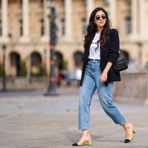 PARIS, FRANCE - FEBRUARY 25: Camille Grandguillote wears sunglasses, a black blazer jacket from Sezane, a black leather bag from Kate Lee, a white t-shirt from "Pas le Time", blue denim jeans pants from Asos, Chanel beige and black slingback shoes, on February 25, 2021 in Paris, France. (Photo by Edward Berthelot/Getty Images)