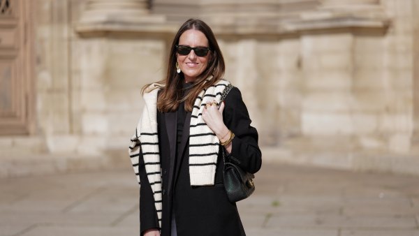woman wearing black coat, striped sweater and white pants