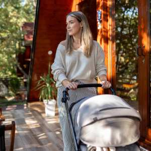 Young smiling mother taking care of her baby in the stroller