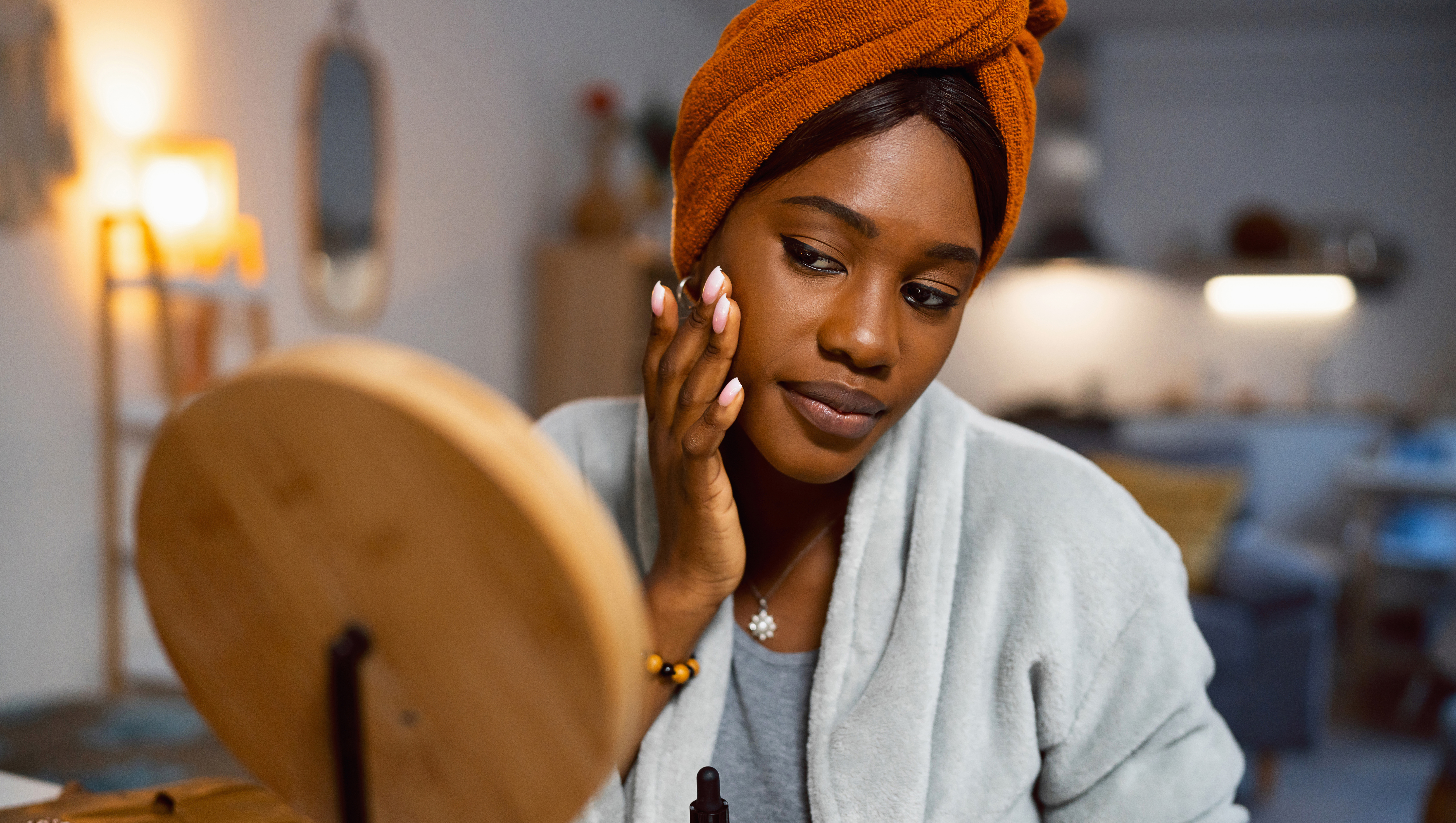 Young woman of Black ethnicity, applying a face serum, while doing a skin care routine