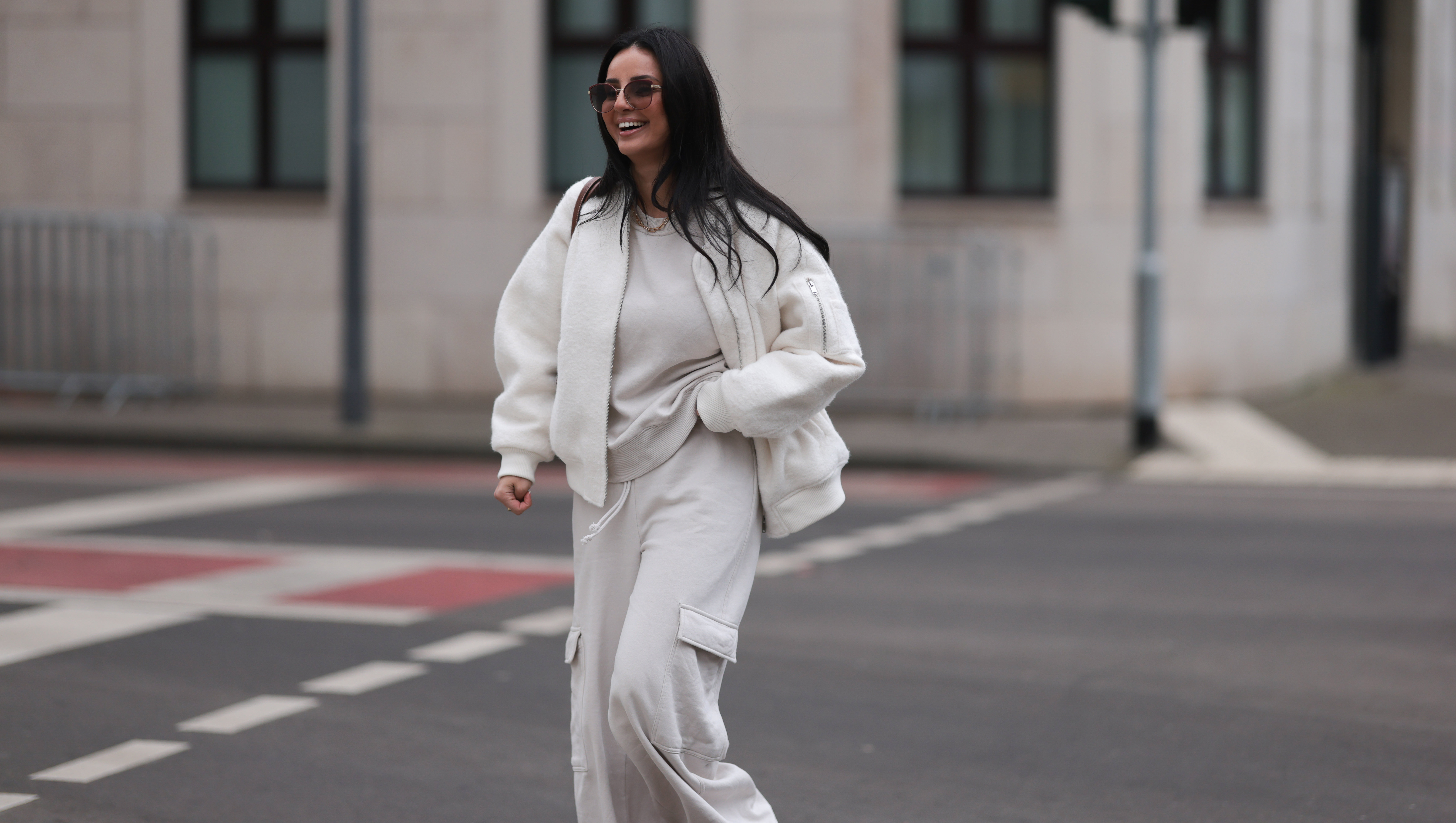 COLOGNE, GERMANY - FEBRUARY 14: Tara Tut seen wearing Gucci brown sunglasses, gold earrings, gold necklace, Zara creamy white cotton oversized sweater, matching Zara creamy white jogger pants / sweatpants, H&M white boucle bomber jacket, Longchamp brown nylon shopper bag, on February 14, 2024 in Cologne, Germany. (Photo by Jeremy Moeller/Getty Images)