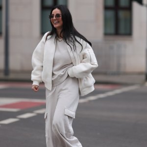 COLOGNE, GERMANY - FEBRUARY 14: Tara Tut seen wearing Gucci brown sunglasses, gold earrings, gold necklace, Zara creamy white cotton oversized sweater, matching Zara creamy white jogger pants / sweatpants, H&M white boucle bomber jacket, Longchamp brown nylon shopper bag, on February 14, 2024 in Cologne, Germany. (Photo by Jeremy Moeller/Getty Images)