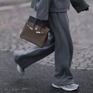 PARIS, FRANCE - JANUARY 25: Fashion Week Guest seen wearing a grey jogging suit, jacket, wide jogging pants and sport sneaker, Hermes taupe Birkin bag outside Hermes Show, during the Menswear Fall Winter 2025/2026 as part of Paris Fashion Week on January 25, 2025 in Paris, France. (Photo by Jeremy Moeller/Getty Images)