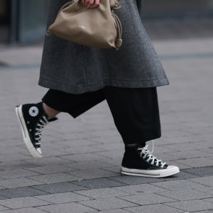 DUESSELDORF, GERMANY - NOVEMBER 08: Maria Barteczko is seen wearing oversized square-shaped aviator glasses with a black frame and narrow silver temples from Victoria Beckham; small chunky hoop earrings in silver from COS; an oversized grey wool coat with notch lapels and large pockets from WENDKYKEI; underneath a black t-shirt with a round neckline paired with black wide-legged culotte pants, both from WENDYKEI; a “Flamenco“ clutch bag in light khaki leather from Loewe; and black high top “All Star Chucks“ from Converse on November 08, 2024 in Duesseldorf, Germany. (Photo by Jeremy Moeller/Getty Images)