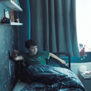 A cop aims a gun at a kid in his bed in Adolescence.