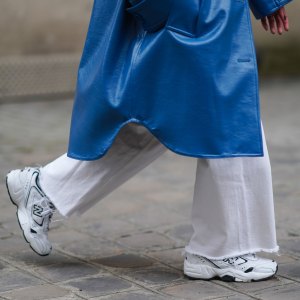 PARIS, FRANCE - MARCH 05: Alexandra Pereira wears a blue long trench coat from Stand Studio, white flare denim jeans from Zara, white sneakers shoes from New Balance, on March 05, 2021 in Paris, France. (Photo by Edward Berthelot/Getty Images)