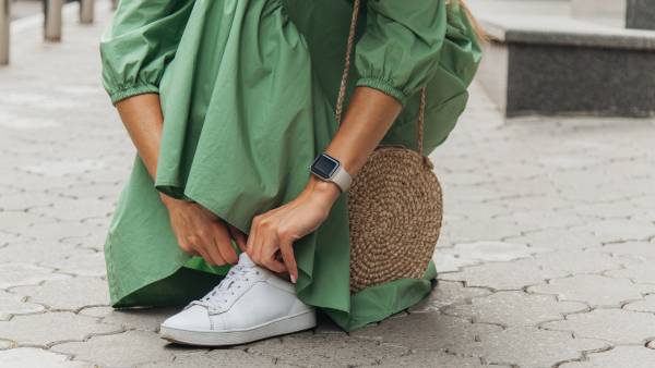 Young woman in a dress lacing her shoe.