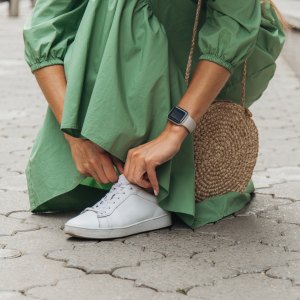 Young woman in a dress lacing her shoe.