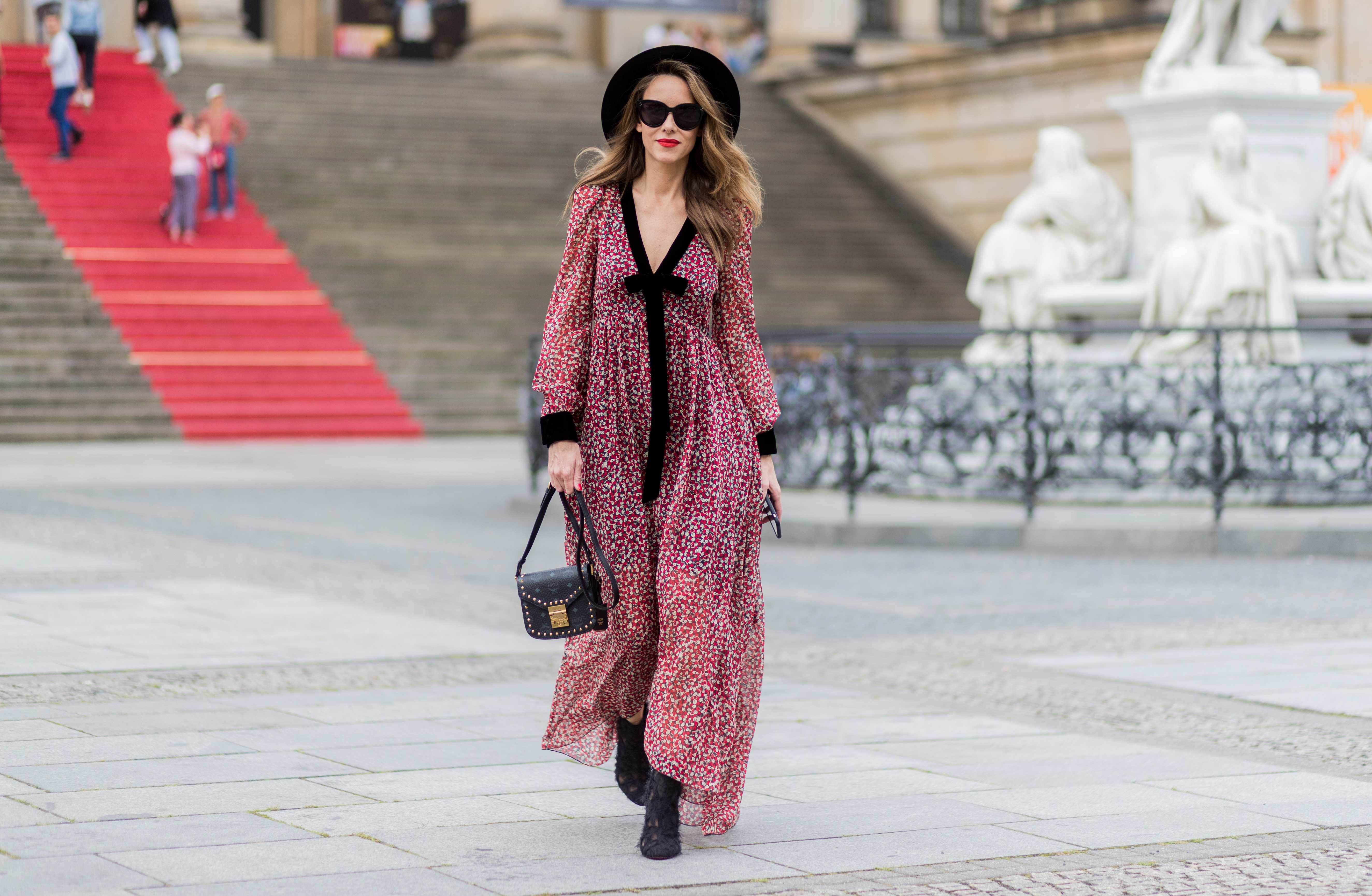 woman in red and black flowy dress and black hat