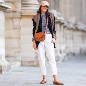 PARIS, FRANCE - OCTOBER 10: Alba Garavito Torre wears a wicker cap, a gingham black and white shirt with Long Sleeve Ruffles from Serendipia, Mom jeans in white by Maison 123 Paris, an oversized black blazer jacket by Munthe, caramel loafers shoes by Church’s, a caramel leather crossbody bag Windsor Paris64, a beige wool sweater over the shoulders, on October 10, 2021 in Paris, France. (Photo by Edward Berthelot/Getty Images)