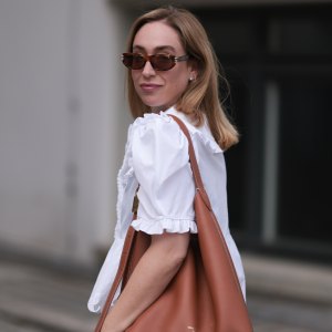 BERLIN, GERMANY - JUNE 11: Sonia Lyson is seen wearing sunglasses with havana frame from Givenchy, silver earrings, a golden necklace, a white blouse with puffed sleeves and ruffled details from Horror Vacui, cream-white wide linen pants from Zara and the “Low Key Hobo” bag in brown leather from Louis Vuitton on June 11, 2024 in Berlin, Germany. (Photo by Jeremy Moeller/Getty Images)